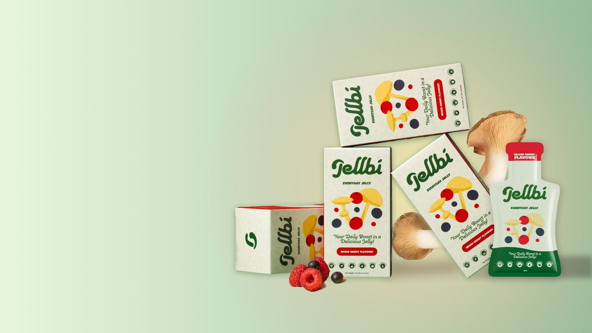 A styled product display of Tellbi dietary supplement packaging, including boxes and a squeeze bottle, arranged on a light green background with mushrooms and berries as props.