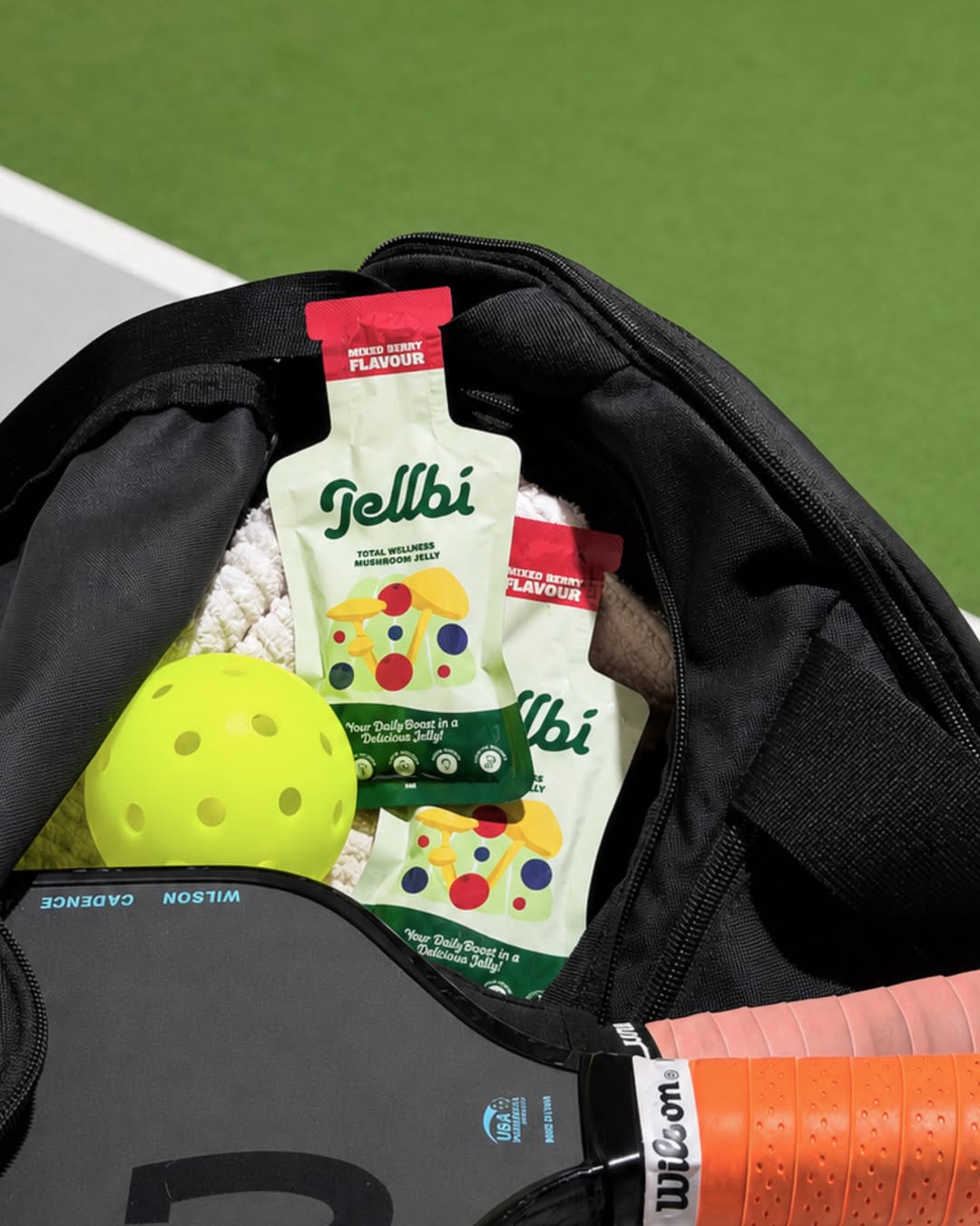 Jellbi sachets packed in a sports bag with a pickleball paddle and ball