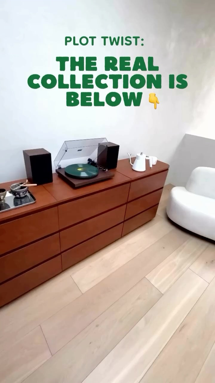 Record player on a wooden sideboard with the text “Plot twist: the real collection is below”